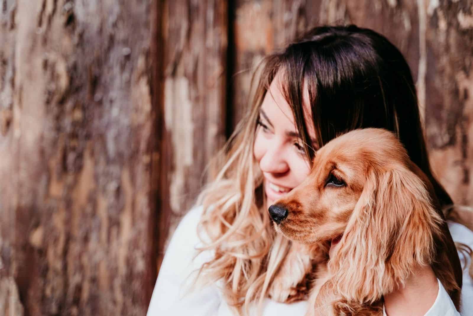 woman carrying dog of cocker spaniel breed outdoors