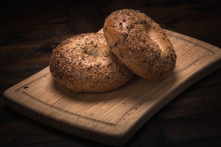 two round bagels with poppy seeds on a cutting board
