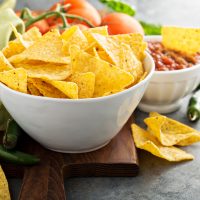 Corn tortilla chips in big bowl with tomato salsa