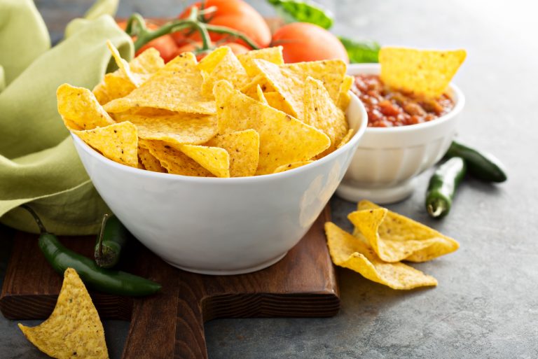 Corn tortilla chips in big bowl with tomato salsa