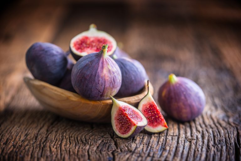 A few figs in a bowl on an old wooden background