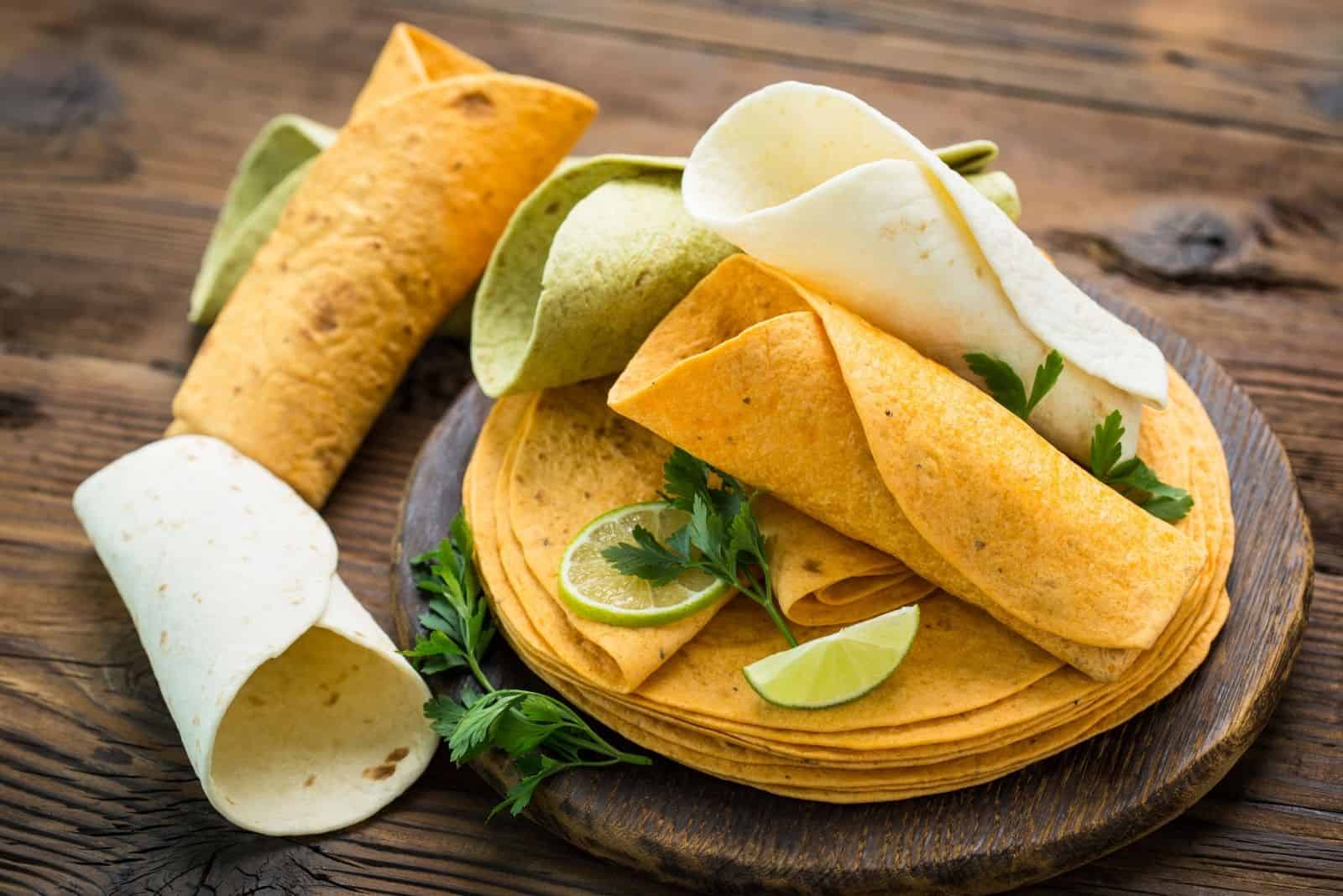 different kinds of tortillas on a wooden plate and table