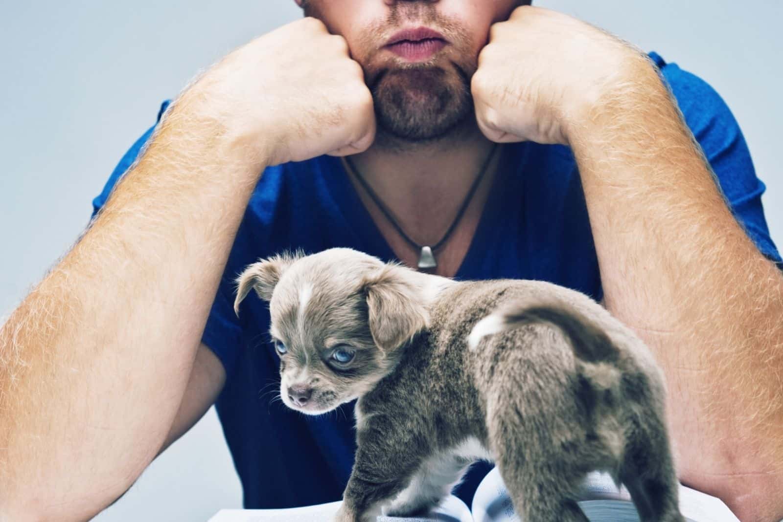 man having a hard time in puppy training on top of a book in the table