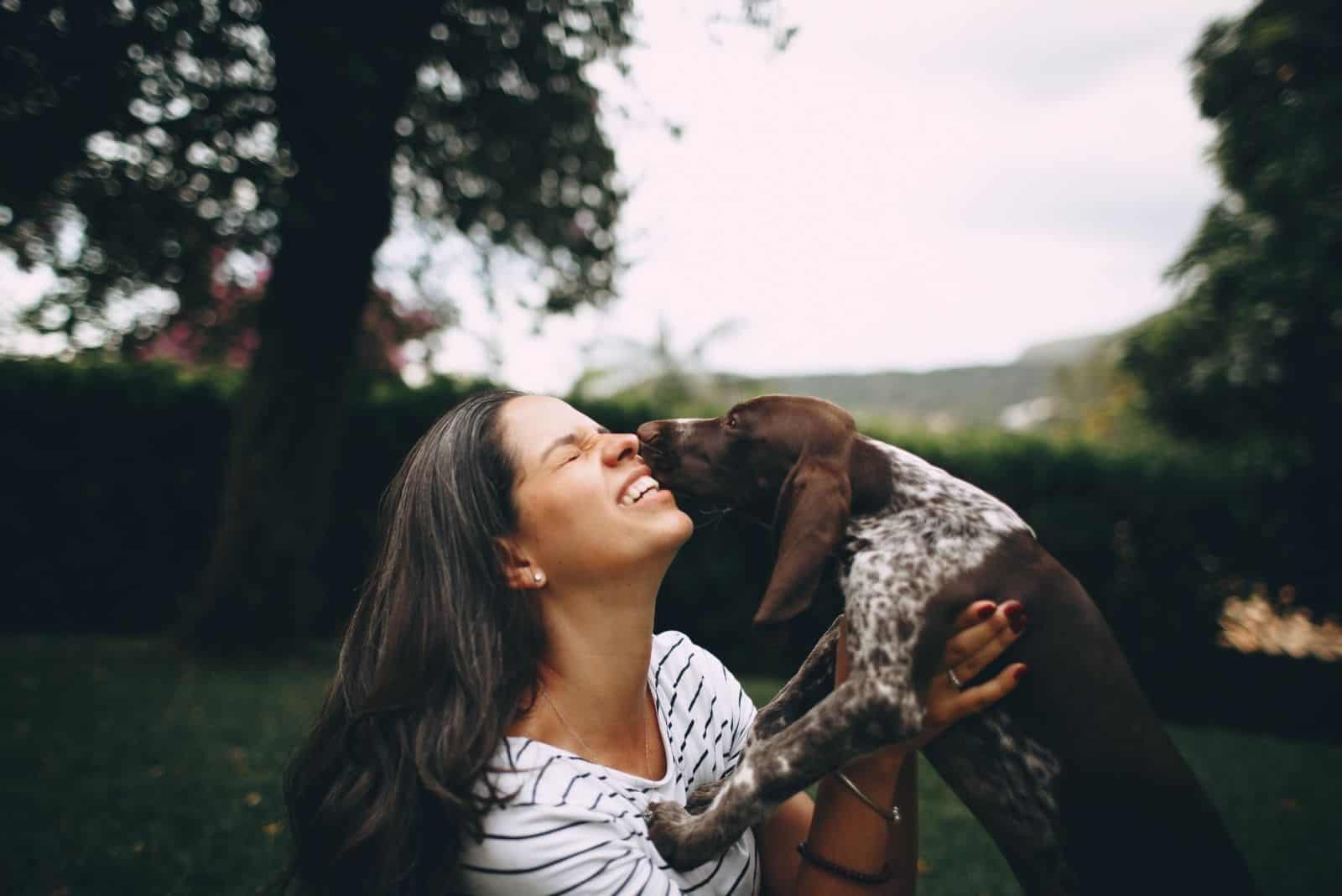 woman kissed by a dog with a blue tick color in its body 