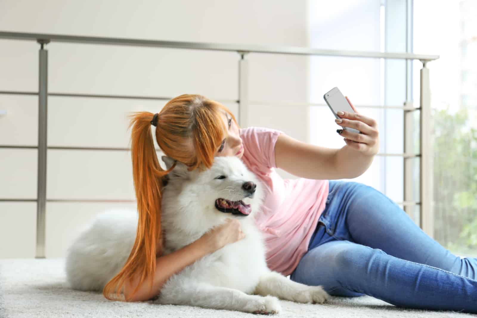 Girl taking selfie with Samoyed dog