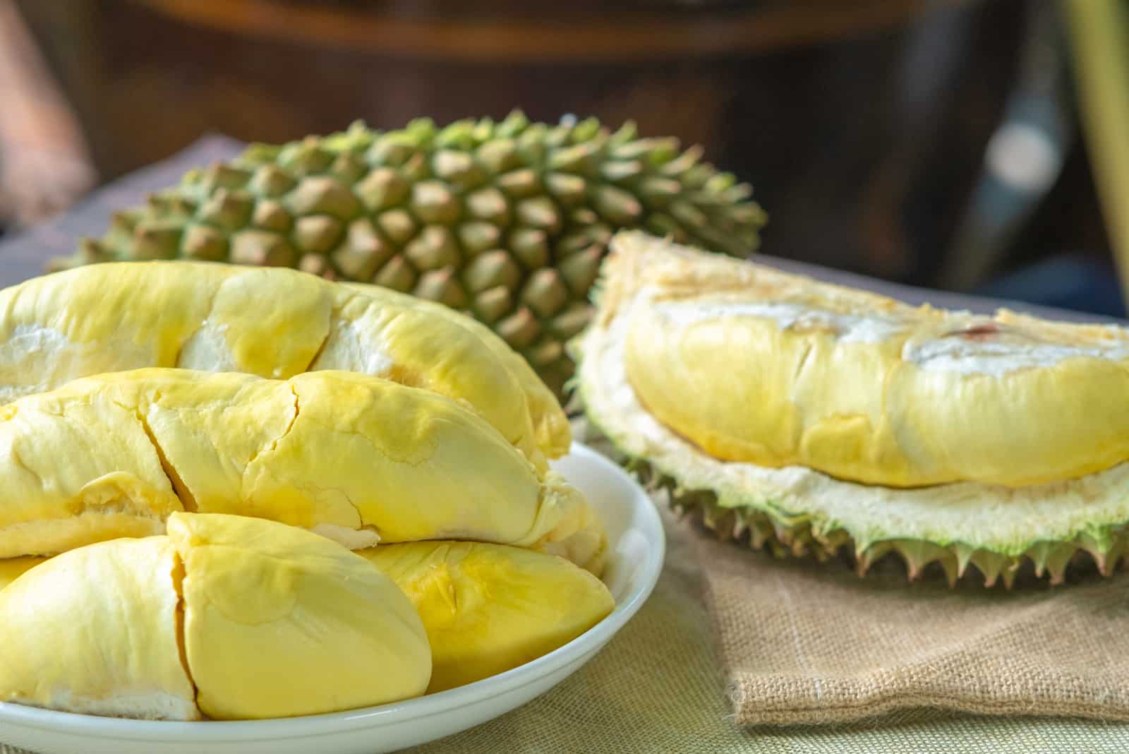 durian on white plate and peeling durian on sack bag