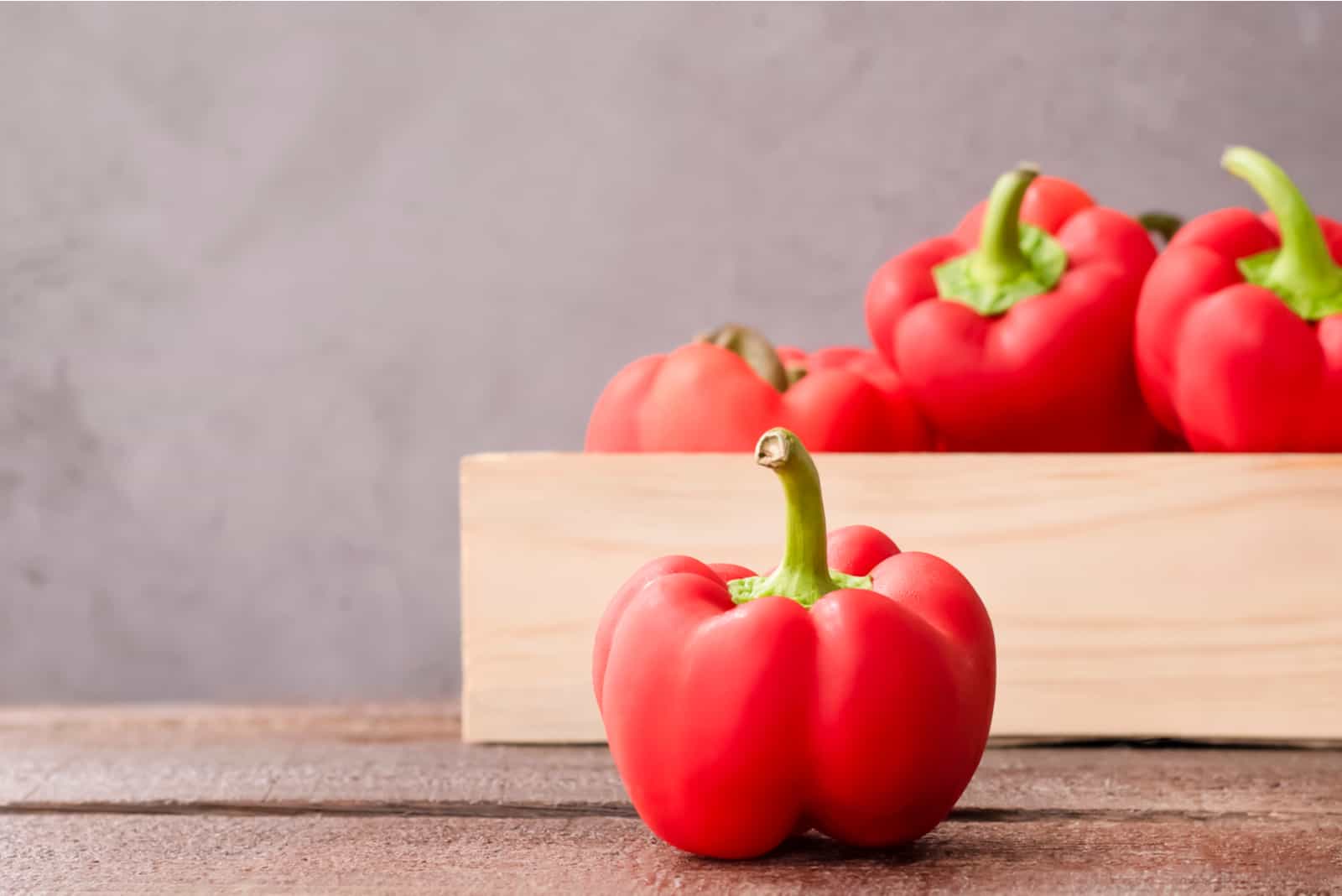 red bell peppers in a wooden box on the table