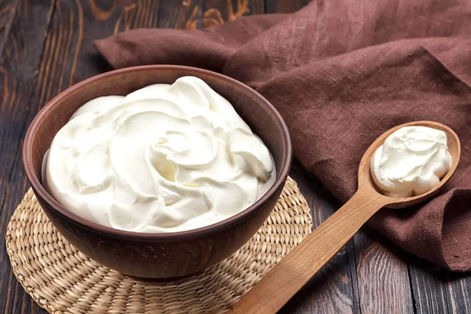 white sour cream in a wooden bowl and spoon