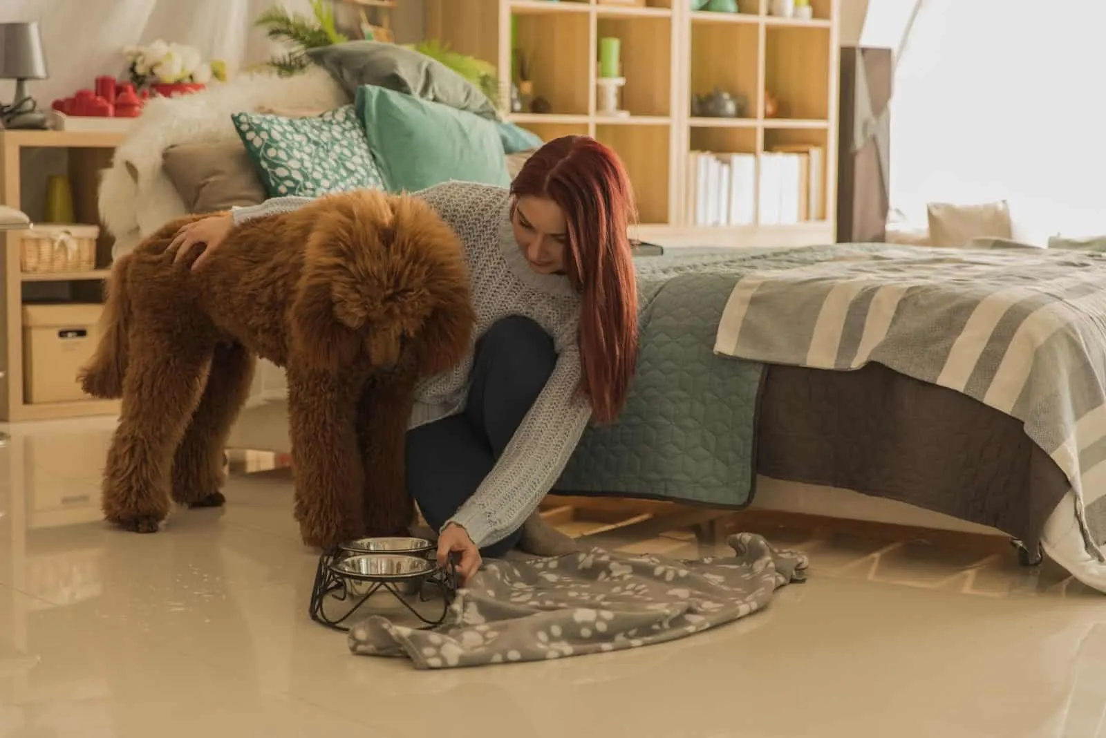 woman giving dog a bowl of dog food at the bedroom