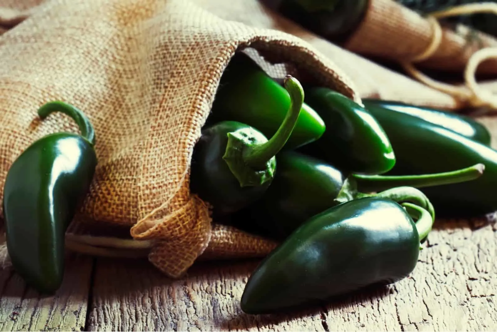 Green jalapeno peppers, old wooden kitchen table background