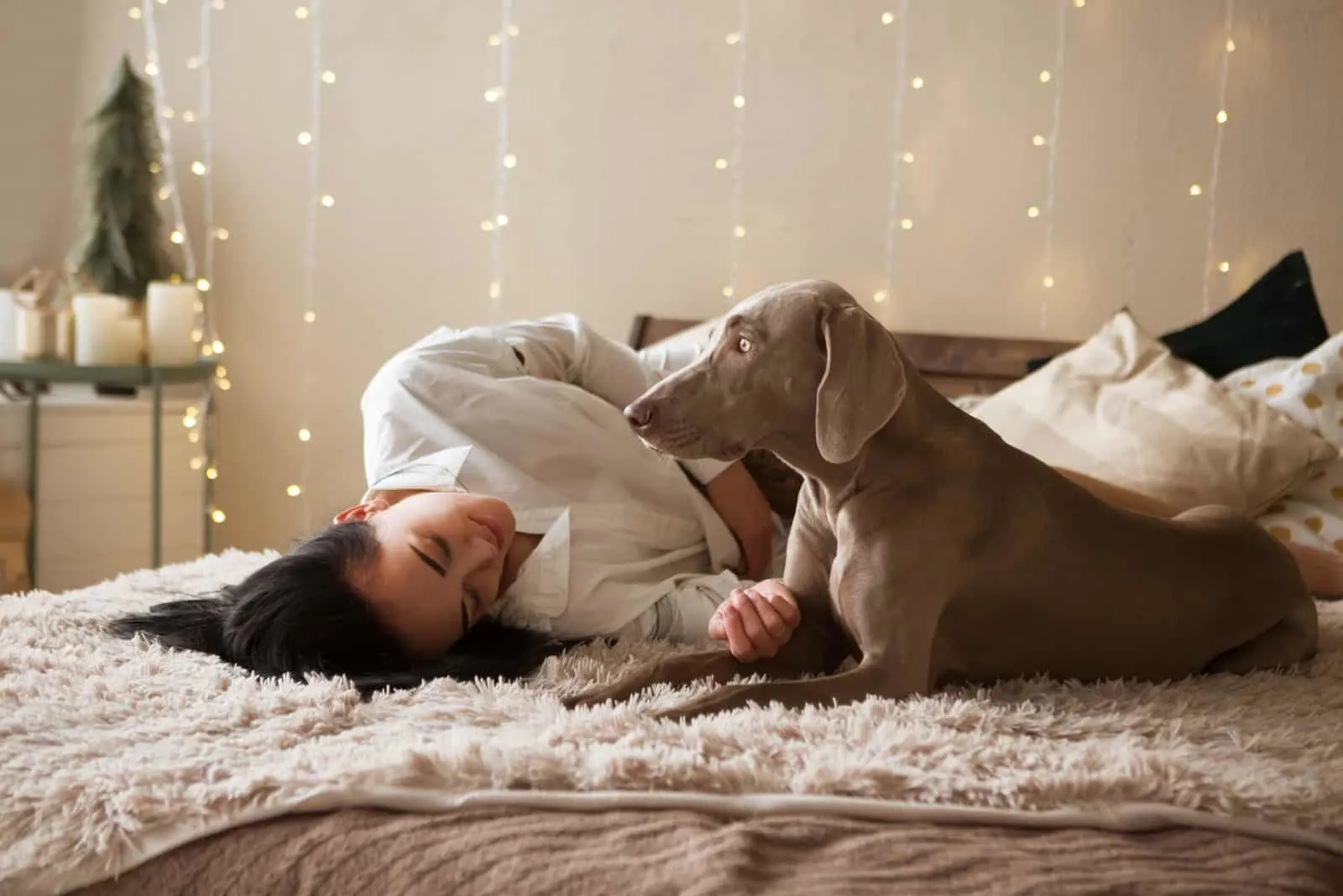 a woman in bed cuddling her dog