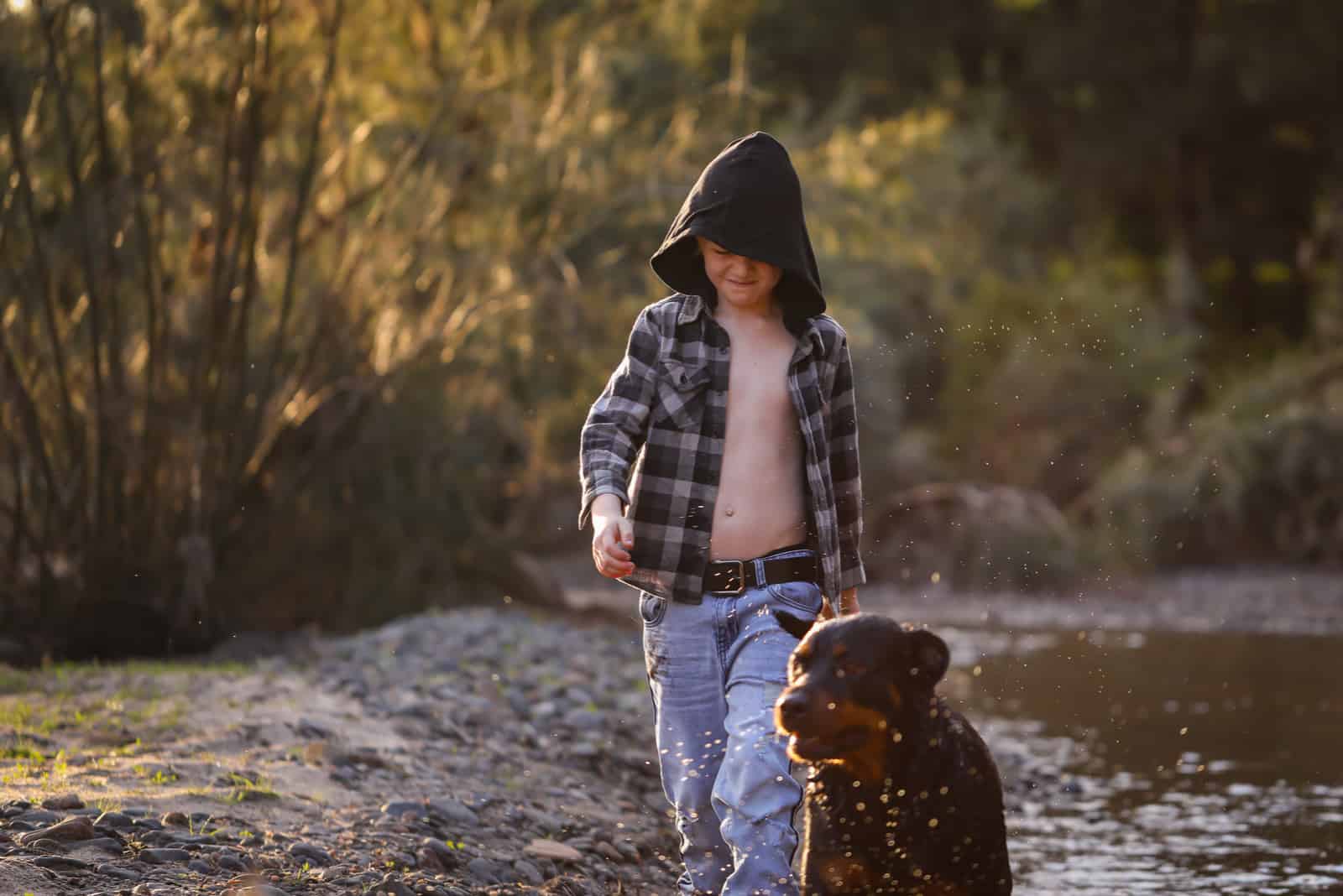 boy walking in nature with his rottweiler dog