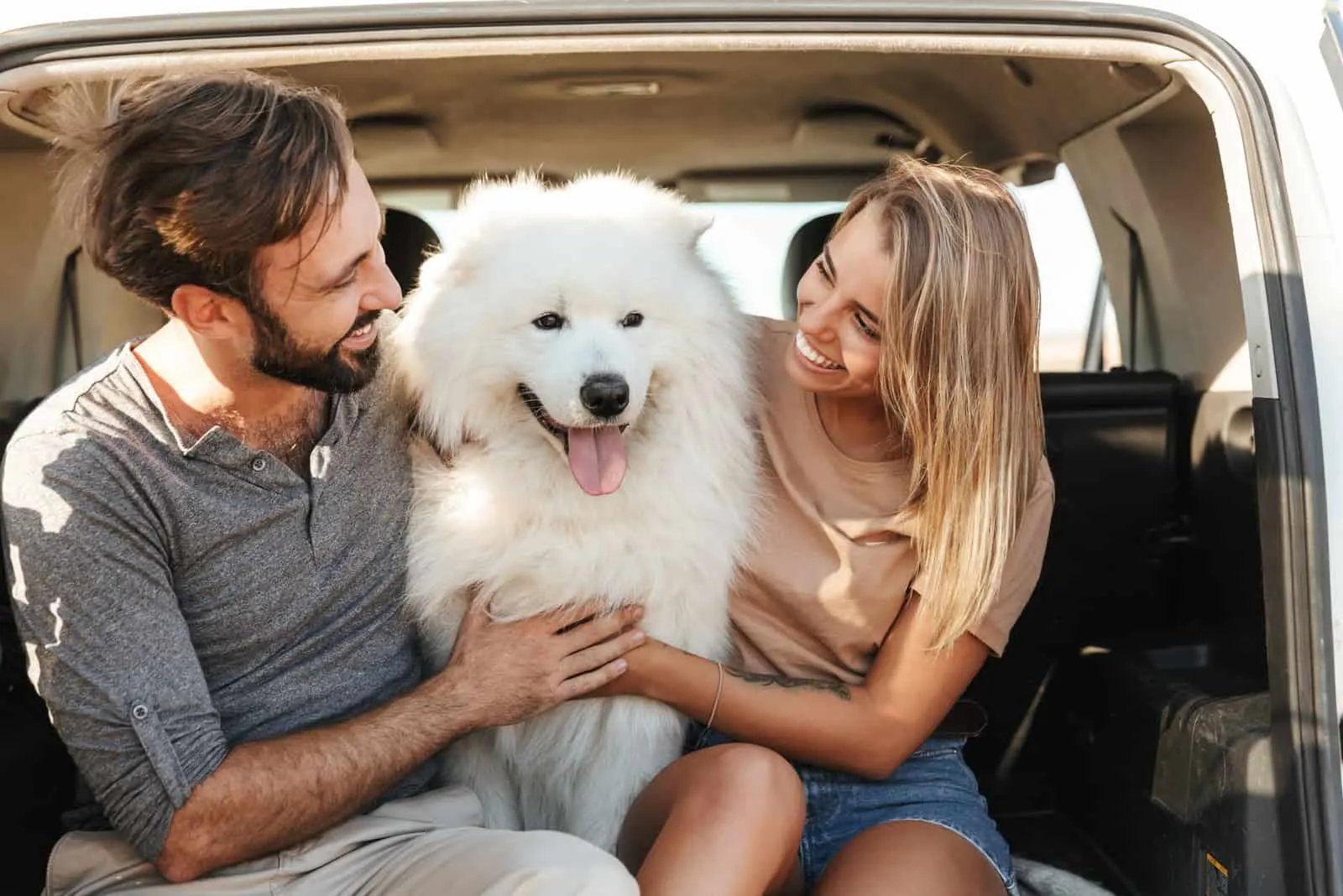 Lovely young happy couple with samoyed