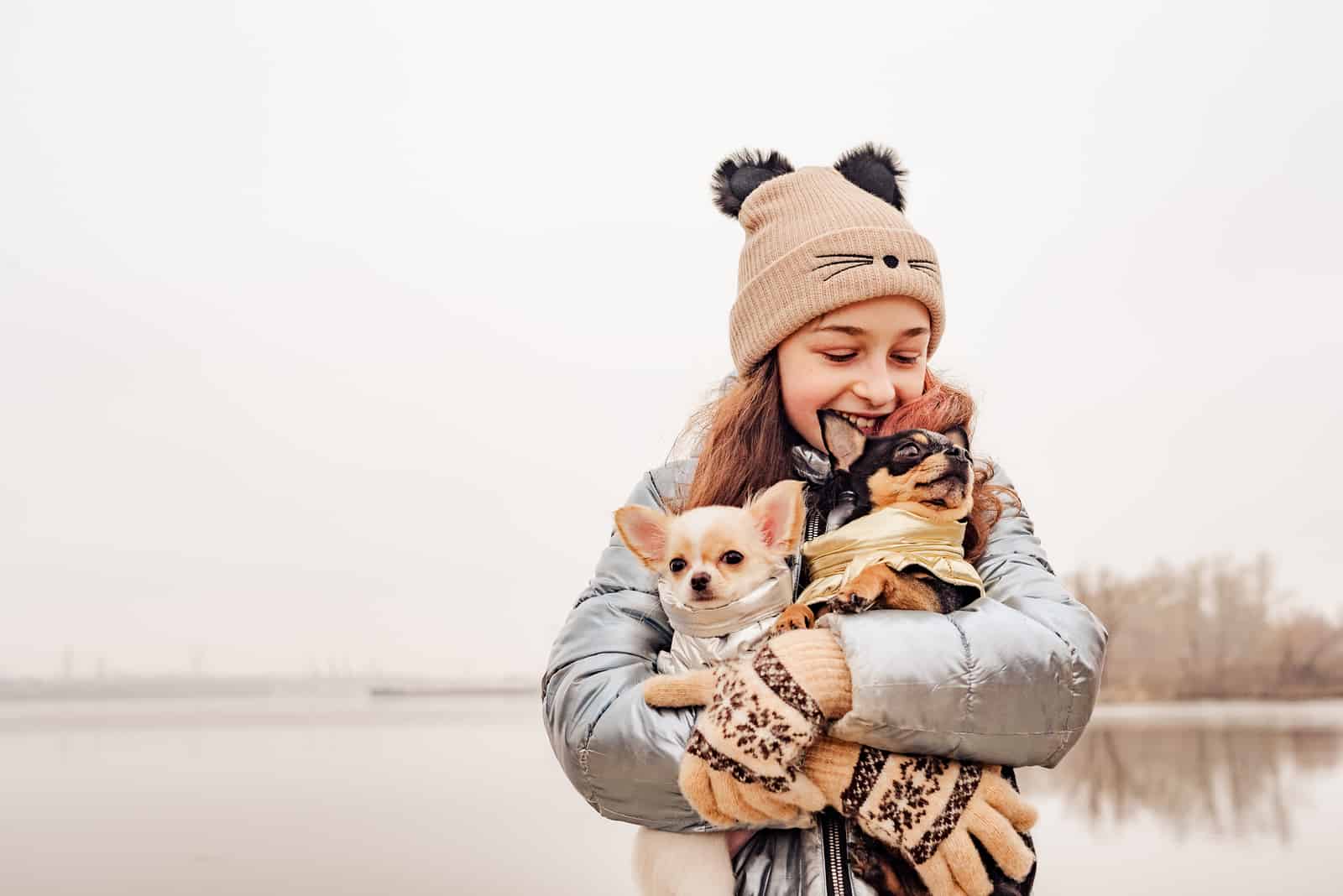 Teenage girl with two chihuahua dogs in her arms