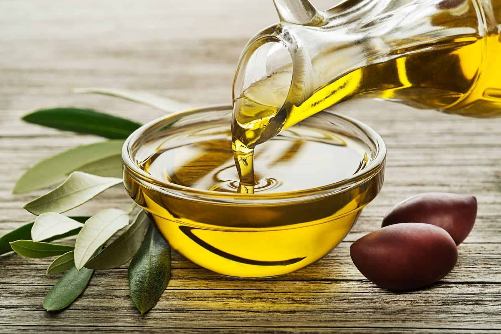 bottle of olive oil pouring close up on a bowl