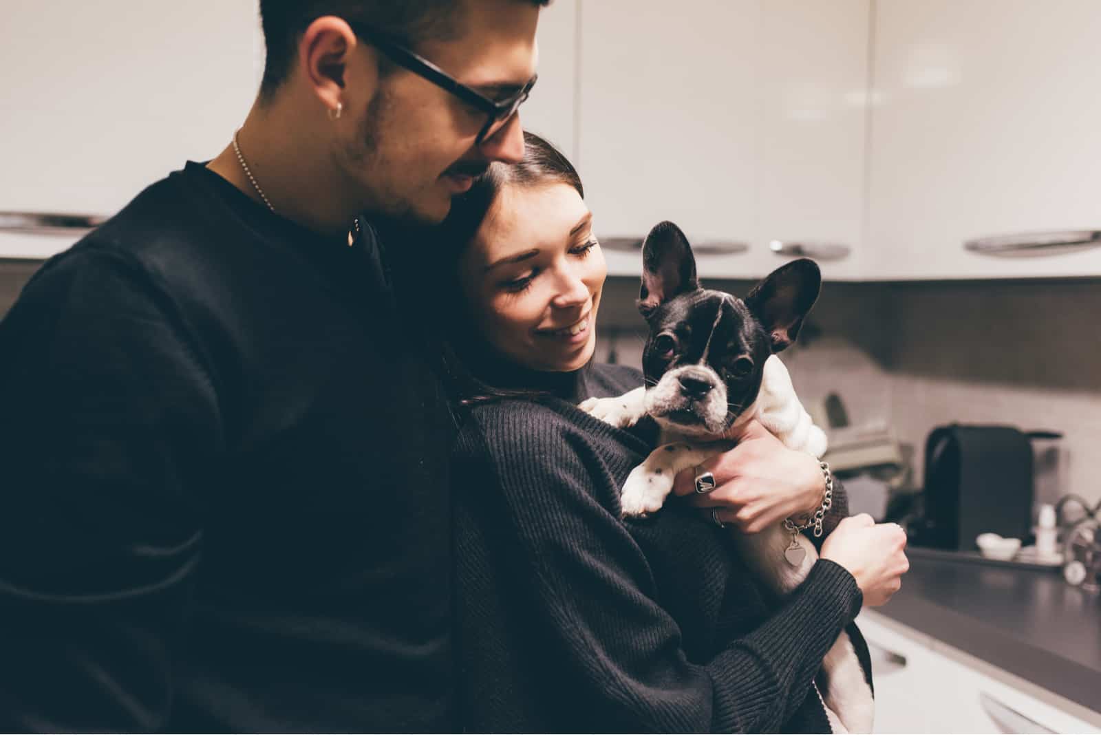 couple indoor in their apartment holding french bulldog puppy