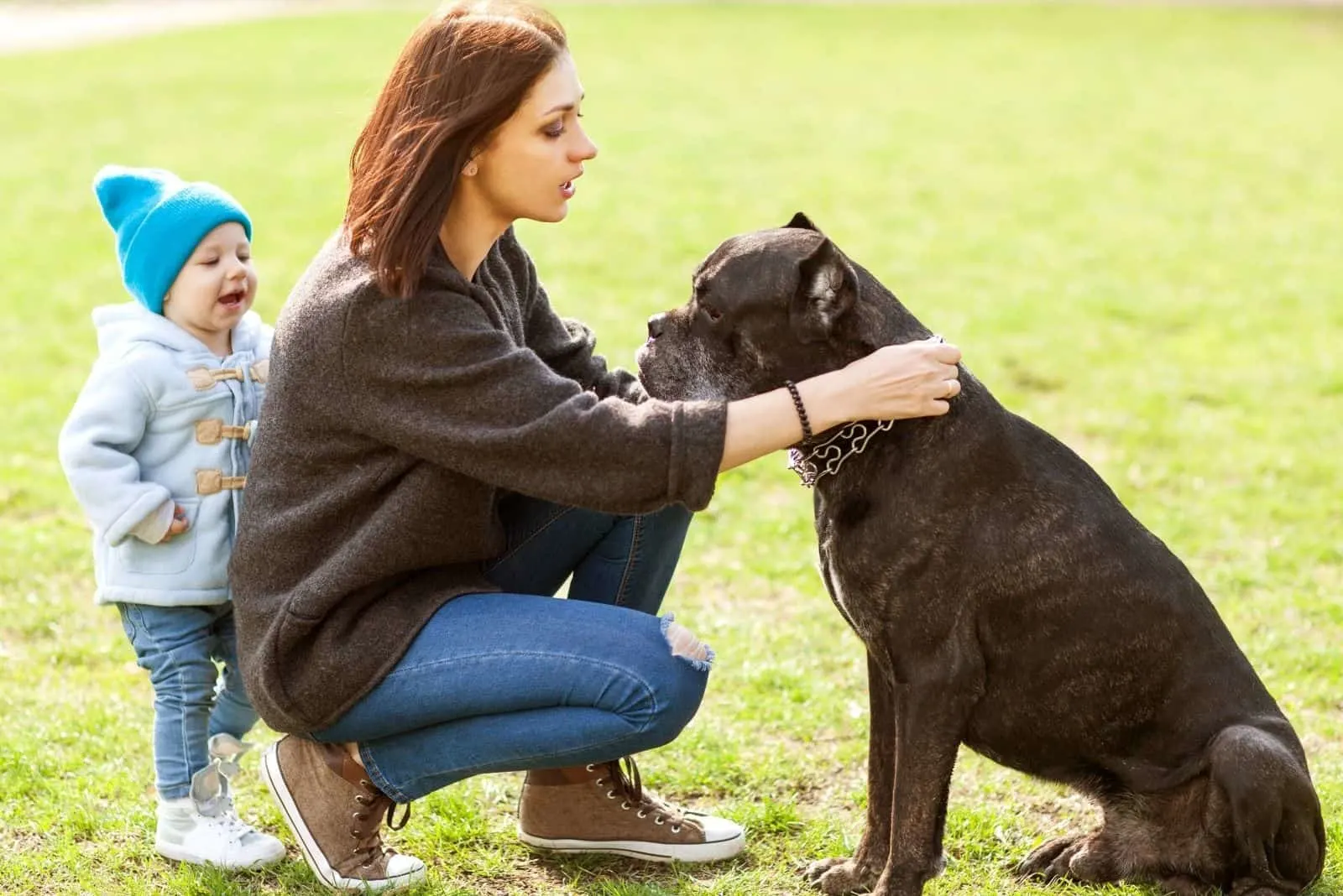 mother and daughter petting a cane corso in the park