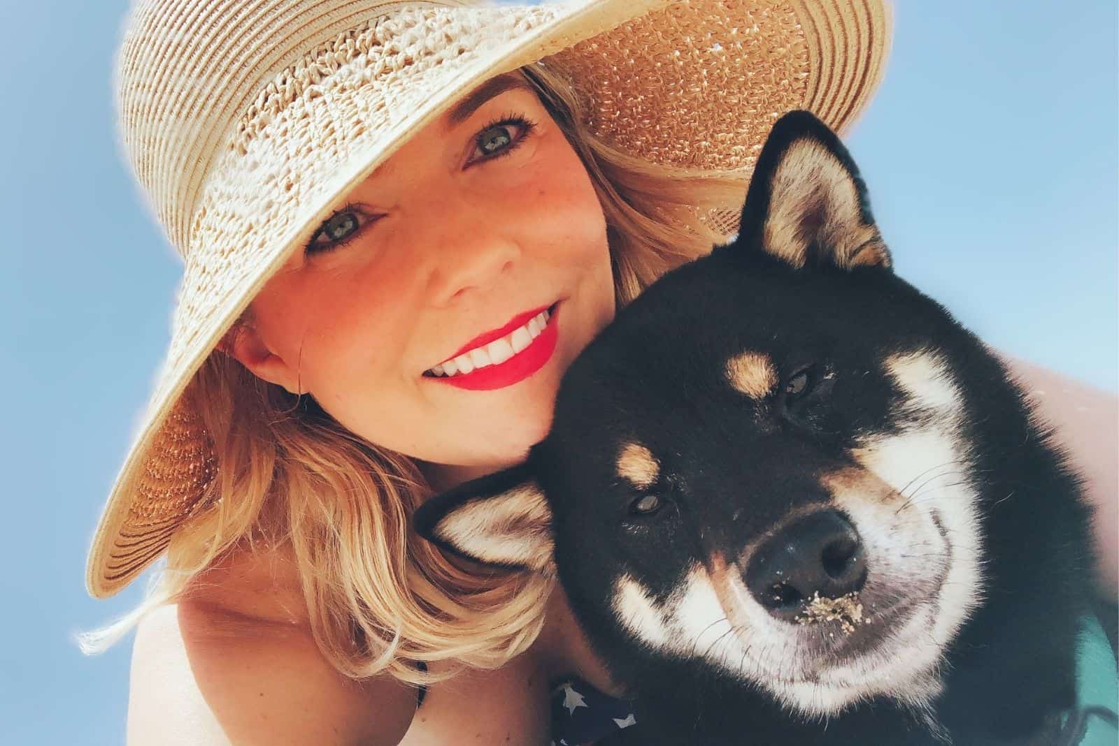 smiling pretty woman posing in the camera with a black shiba inu