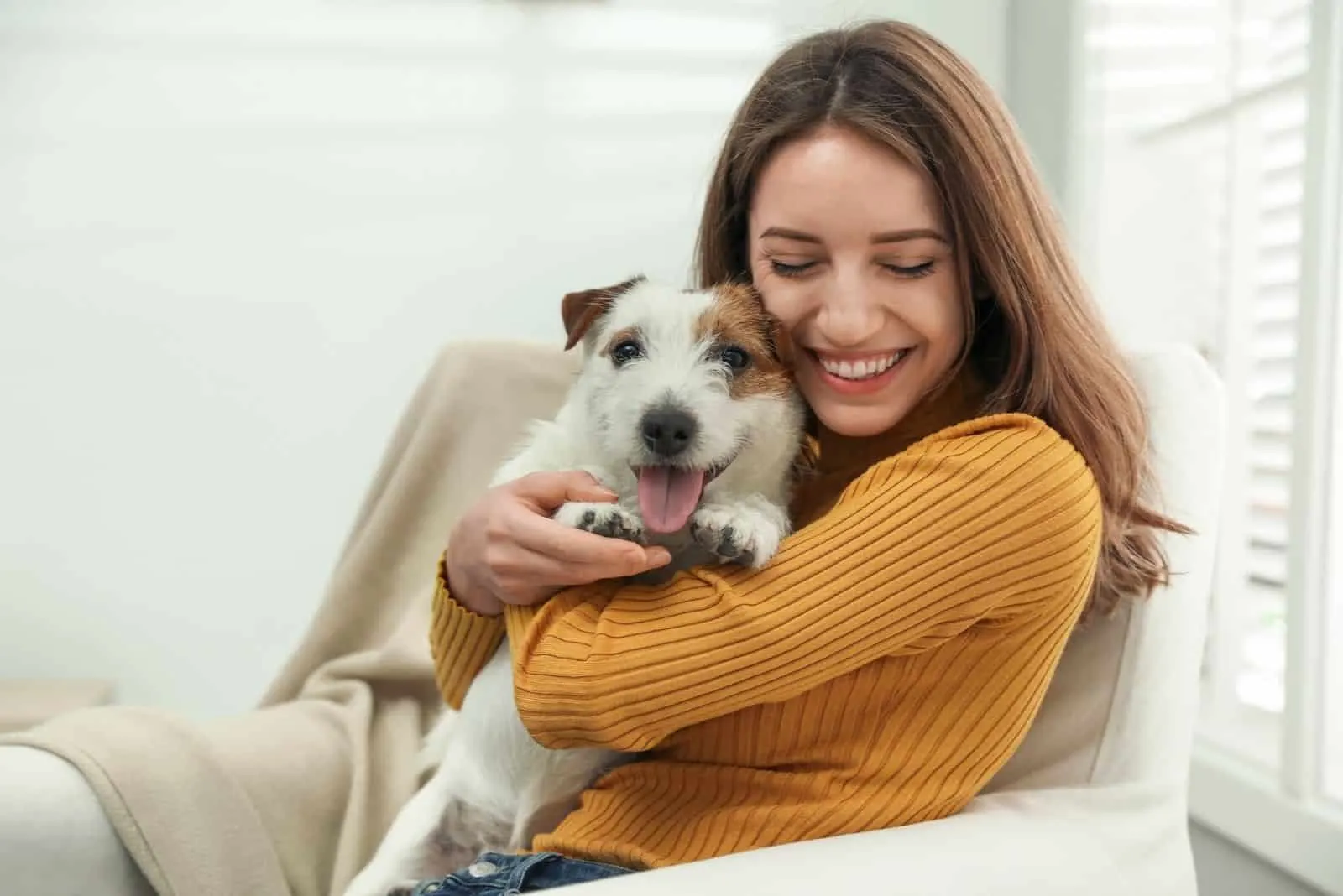 young woman hugging a dog and sitting in the sofa
