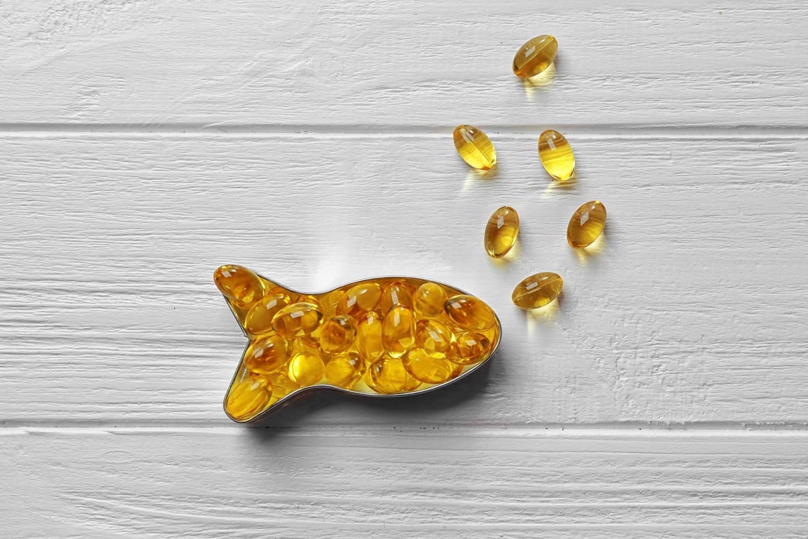 capsules of cod liver oil arranged in fish shape in a wooden table