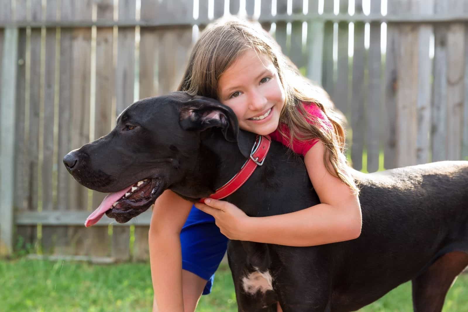 kid hugging dog black great dane mix 