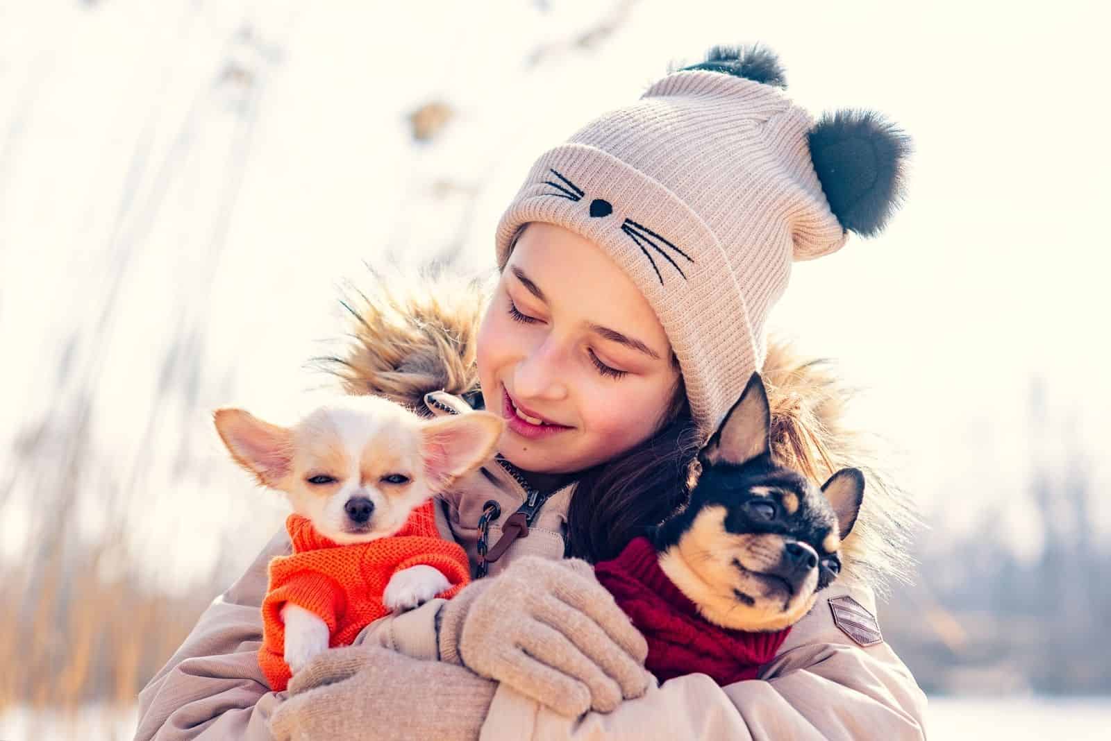 teenage girl hugs a puppy and mother dressed chihuahua during winter