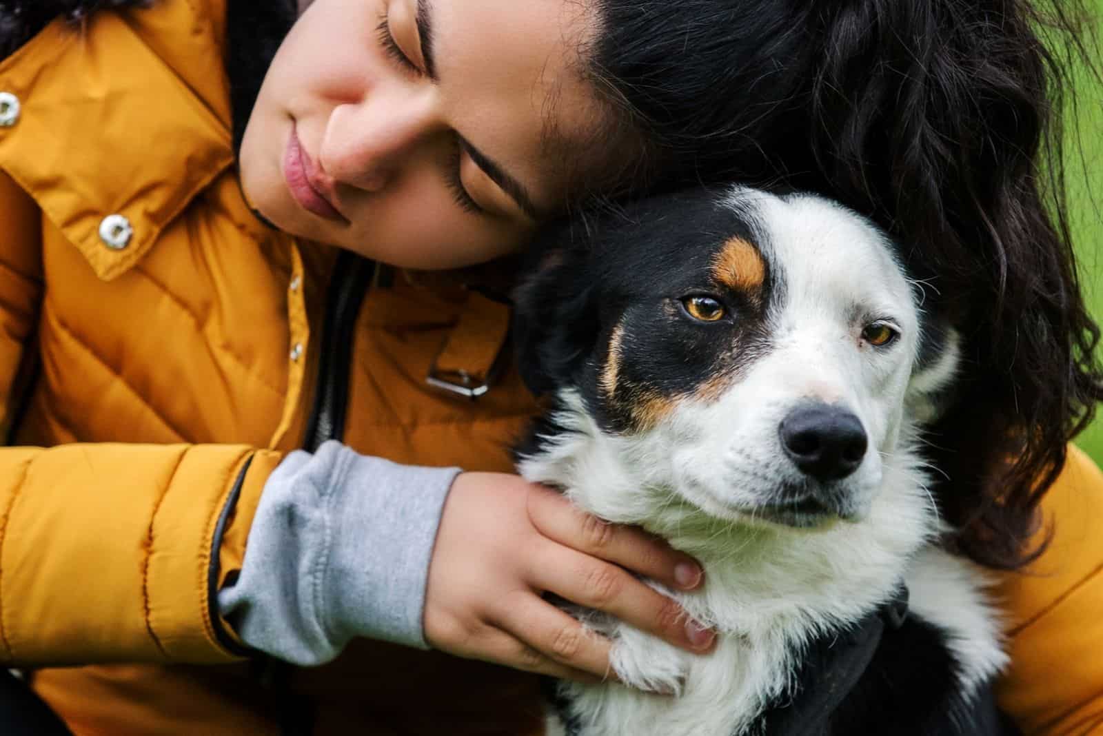 Young female hugging her half-white faced border collie dog