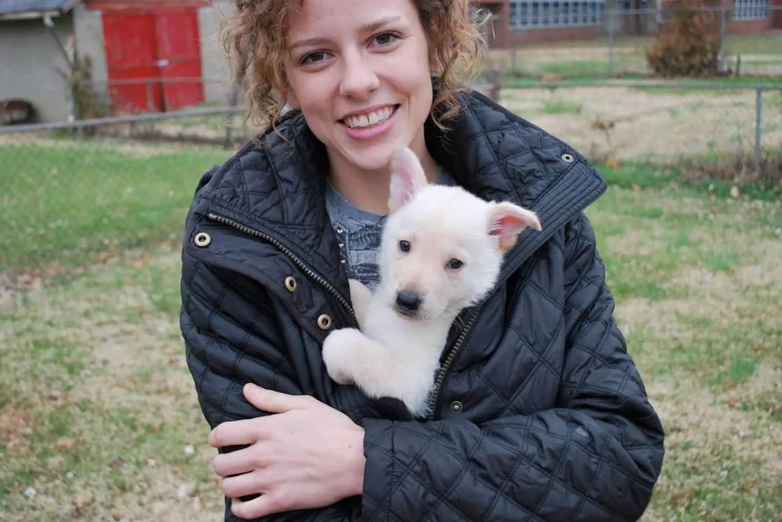 woman holding pet in her arms a white german shepherd puppy