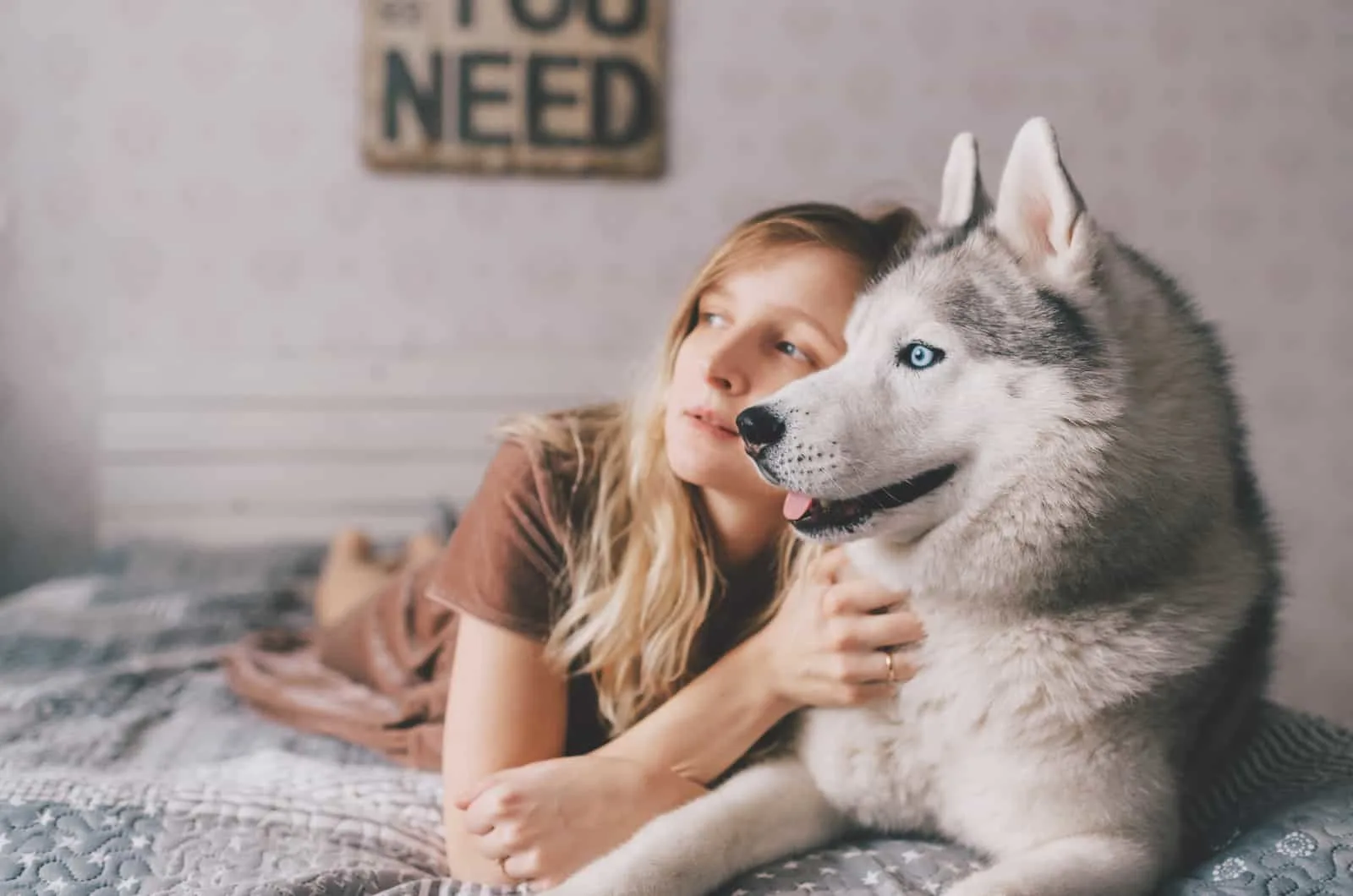 girl lying in bed with her husky