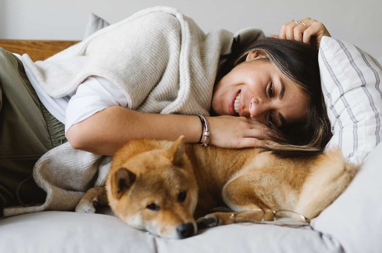 woman lies with her shiba inu pet