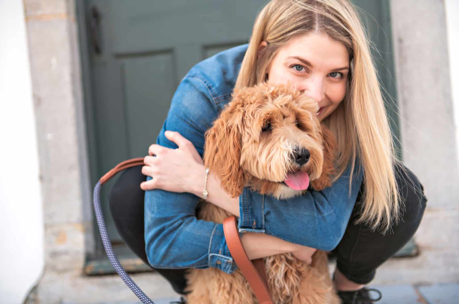 woman hugging labradoodle outdoors