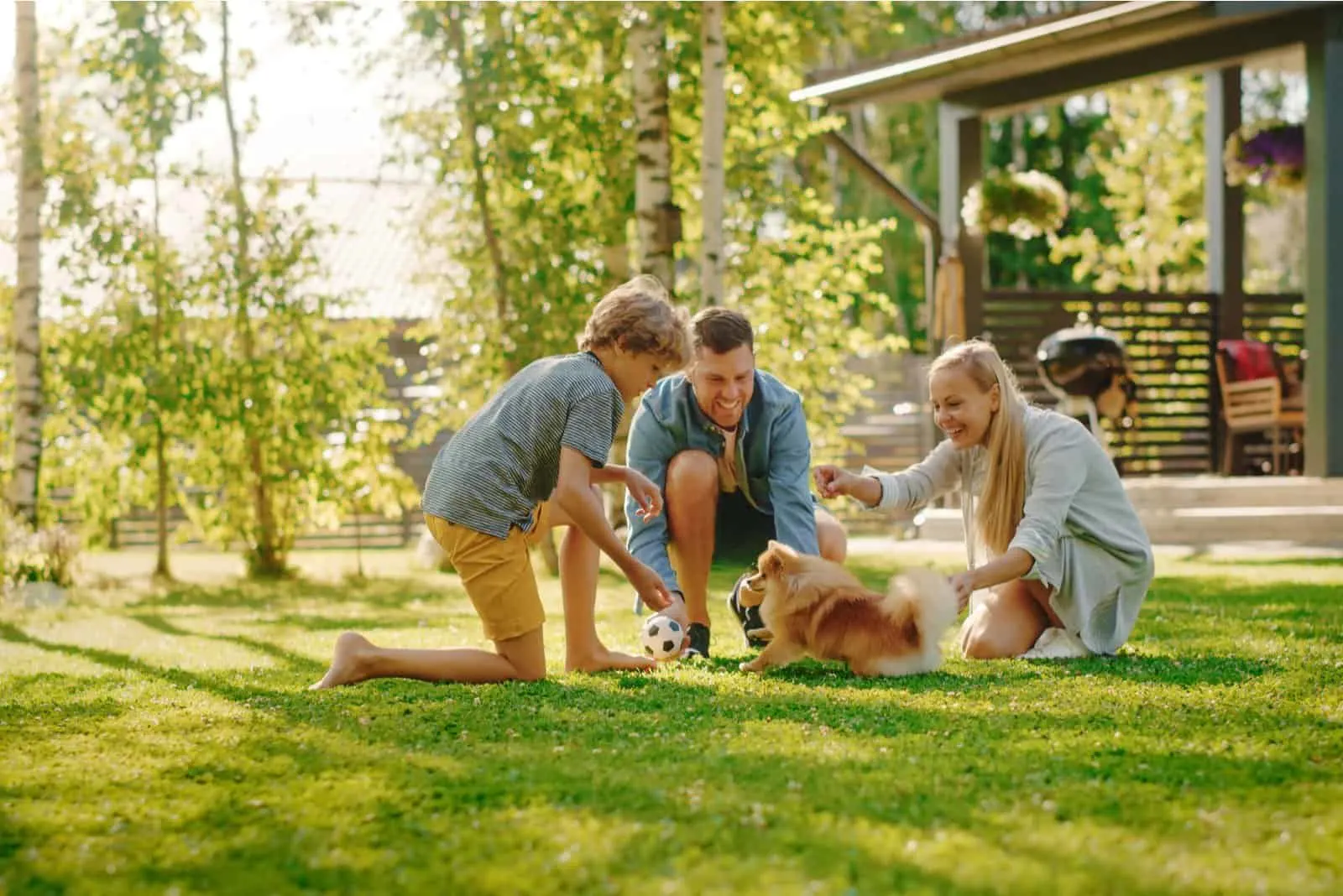 happy family playing with pomeranian dog in garden