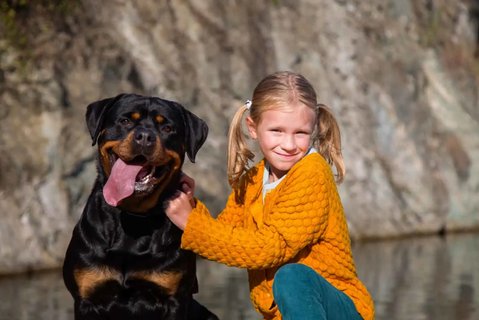 blonde girl posing next to her rottweiler pet