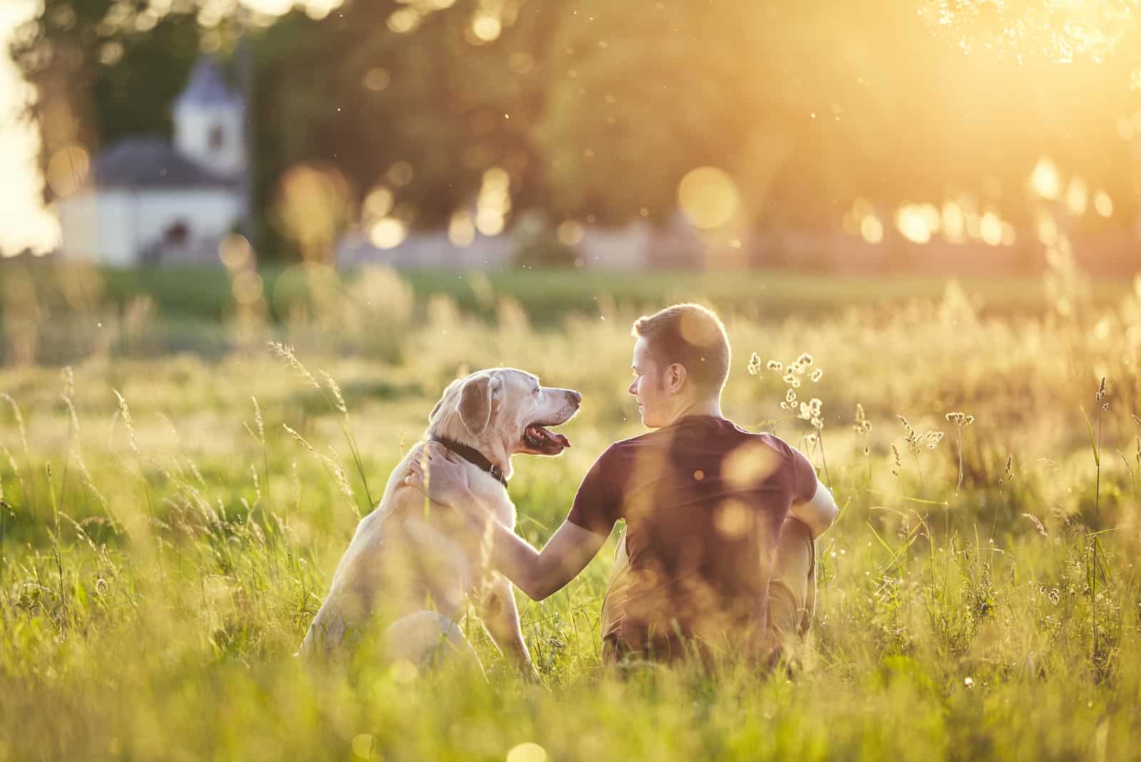 owner and dog sitting on grass