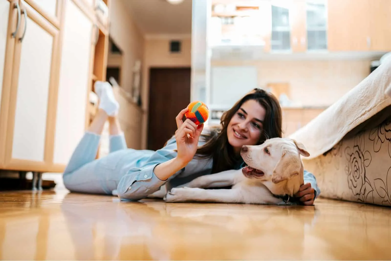 Cheerful woman playing with her dog in apartment