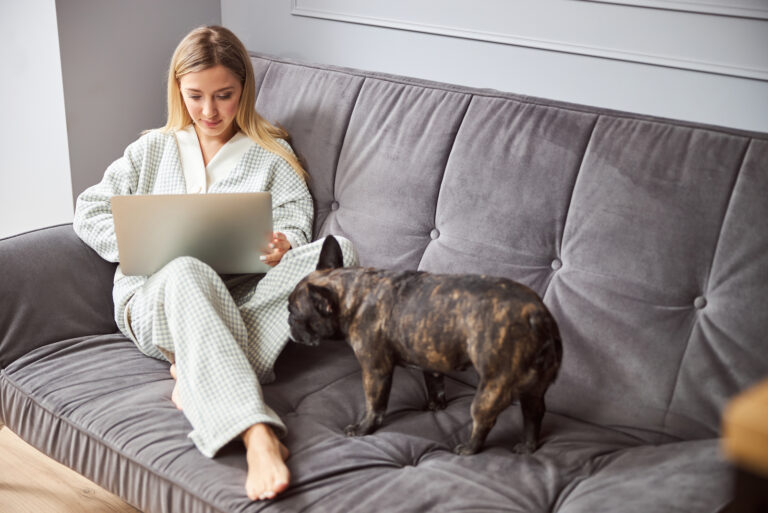 woman working on laptop with dog next to her