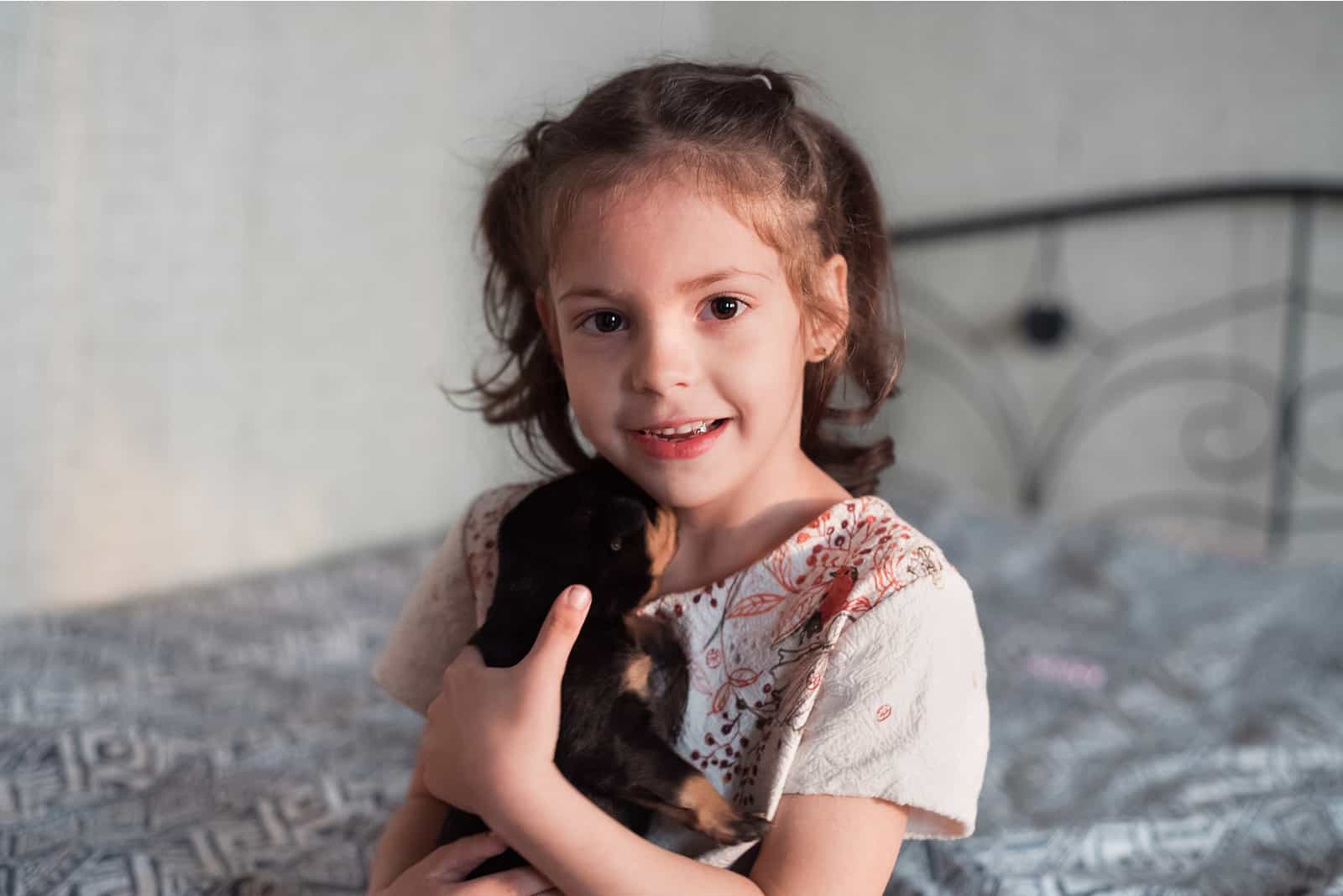 A beautiful girl hugs a little rottweiler puppy