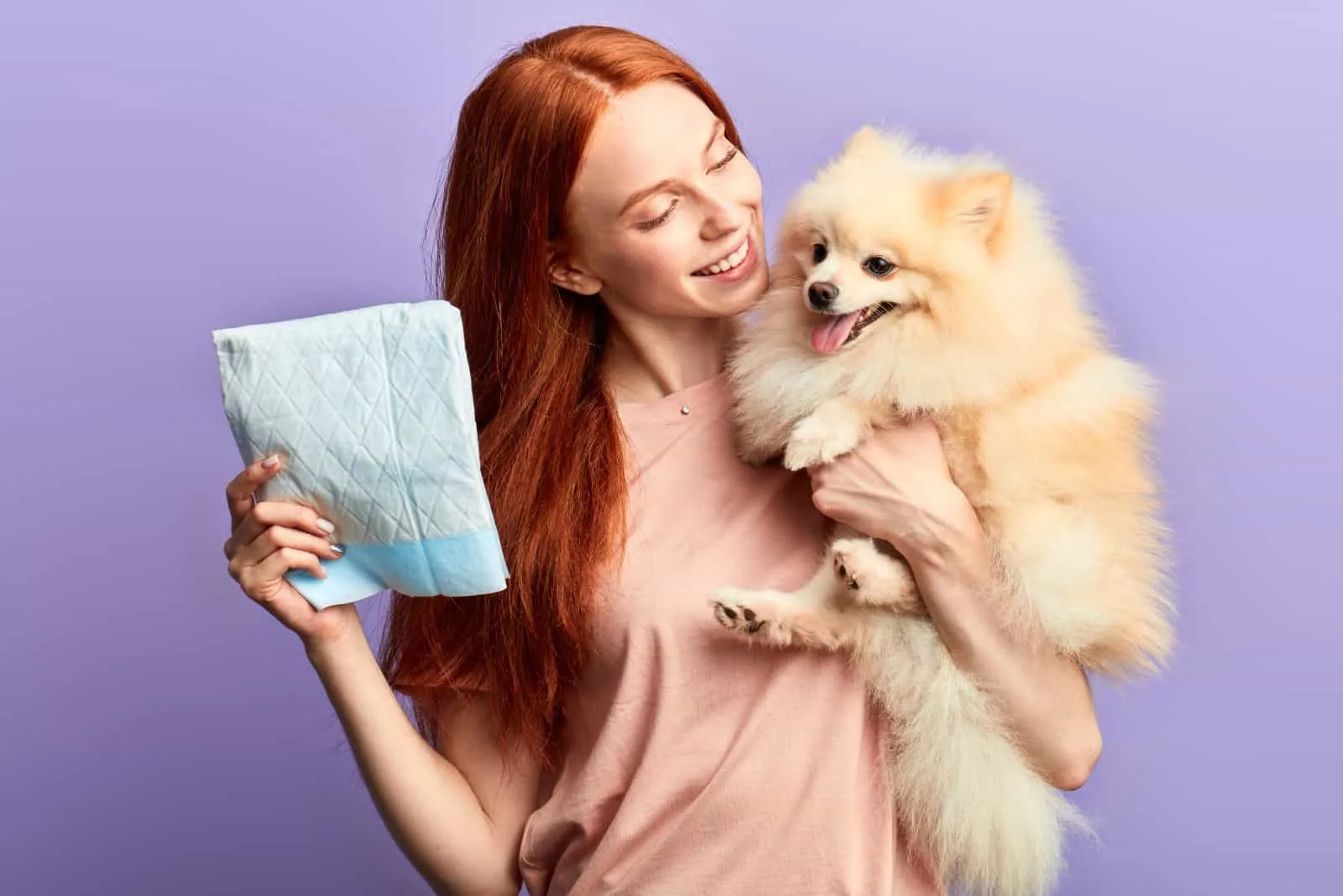 a pomeranian in the arms of a woman with diapers
