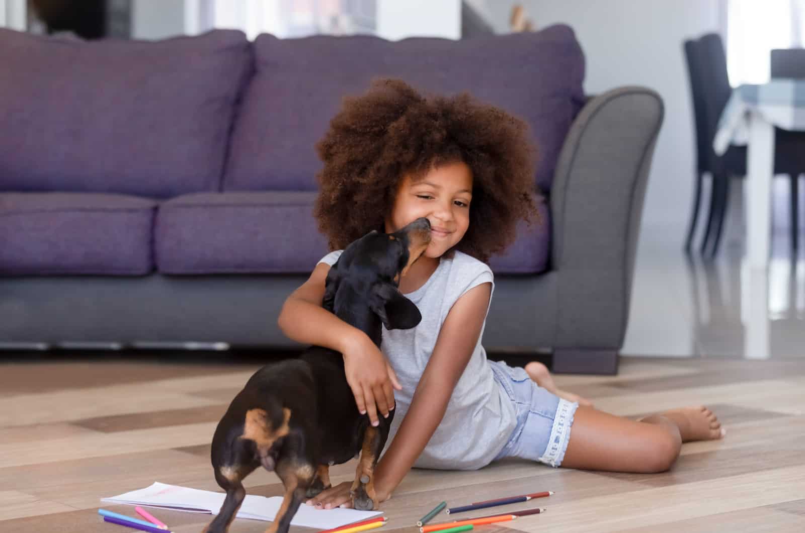 african girl distracted from drawing playing caressing dachshund puppy