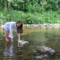 a woman in the water with a french bulldog