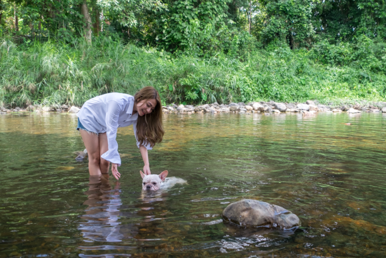 a woman in the water with a french bulldog