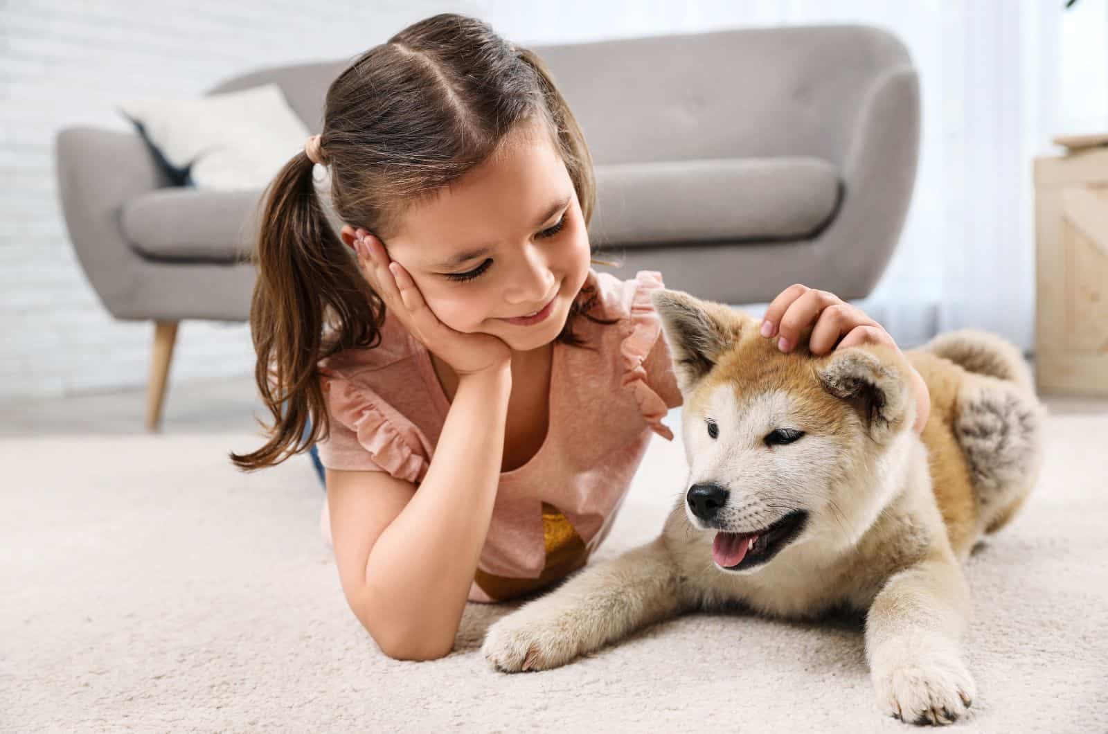 Happy girl with Akita Inu dog on floor
