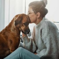 woman kissing a sad dog