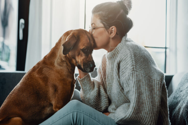 woman kissing a sad dog