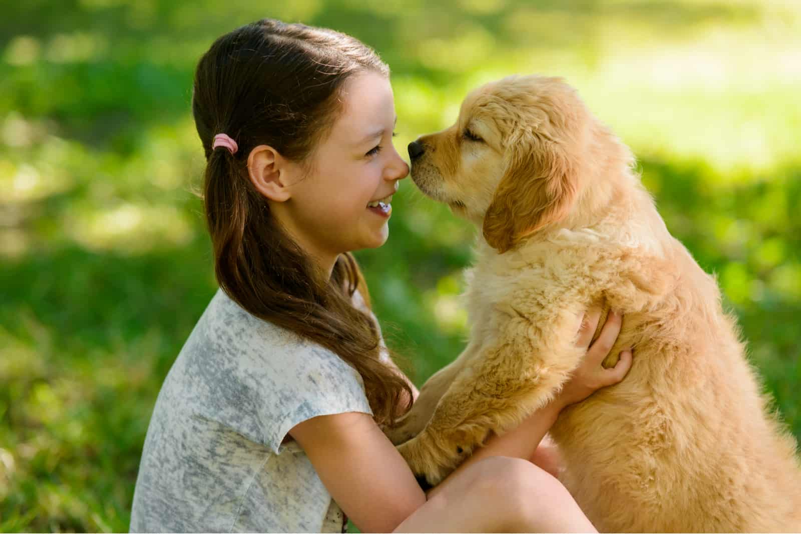 girl holding a golden retriever puppy