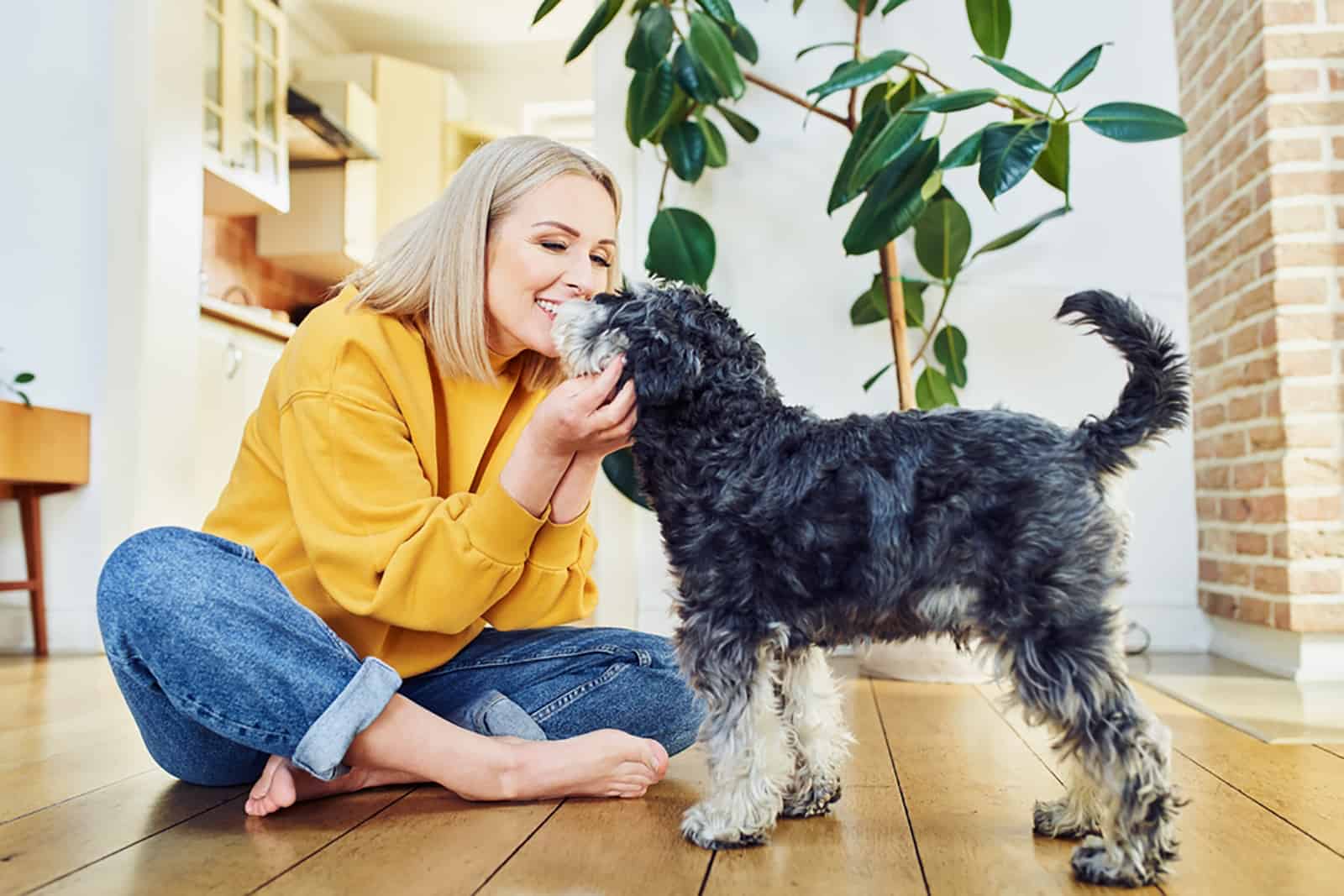 smiling woman playing with her dog indoors
