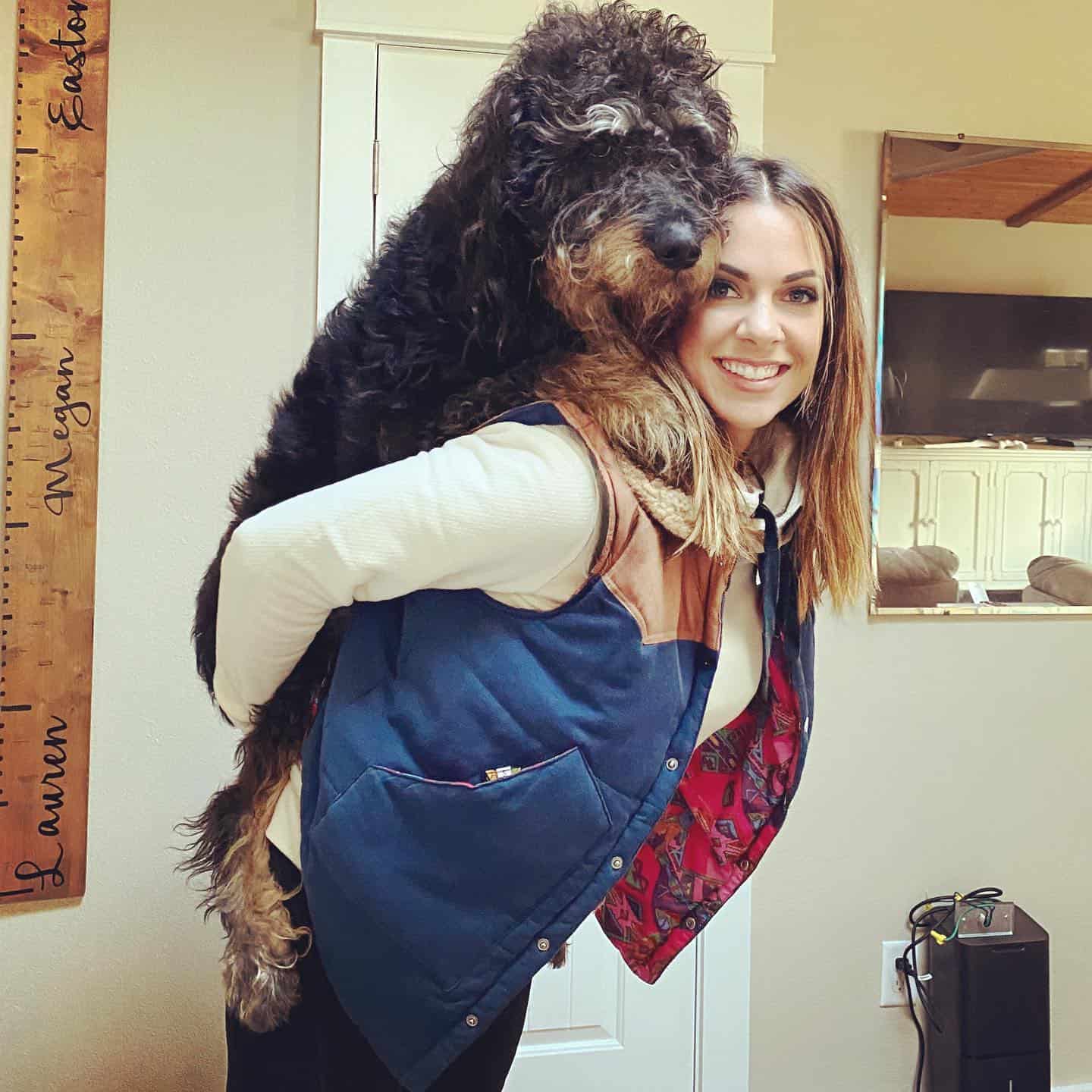 woman carrying big rottie doodle dog on her back