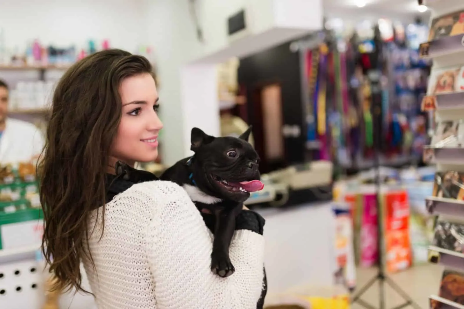 Beautiful brunette woman with her French bulldog puppy in pet shop
