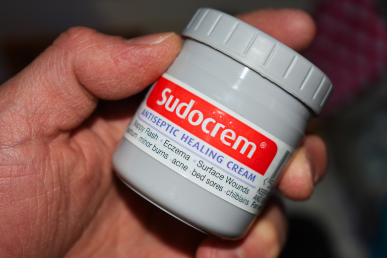 a man holds Sudocrem in his hand