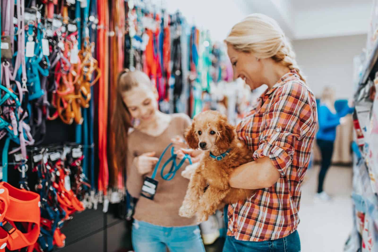 Mother and daughter with their poodle puppy in pet shop